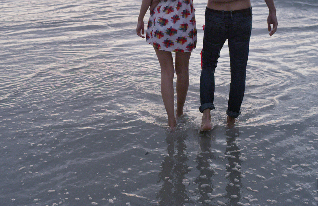 Young couple walking in ocean surf
