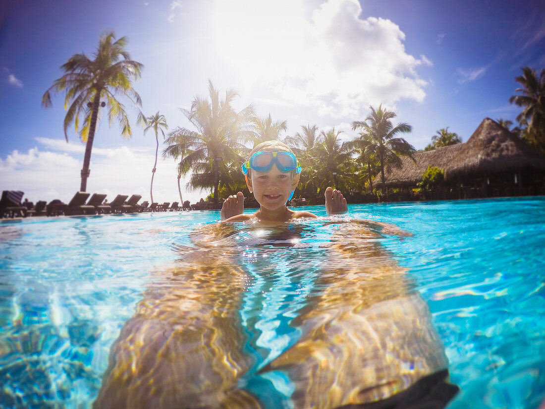 Boy in sunny tropical swimming pool