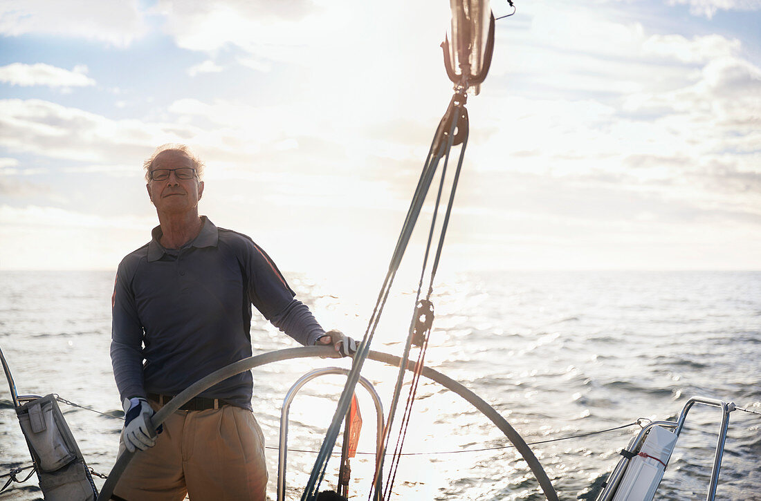 Retired man sailing steering sailboat