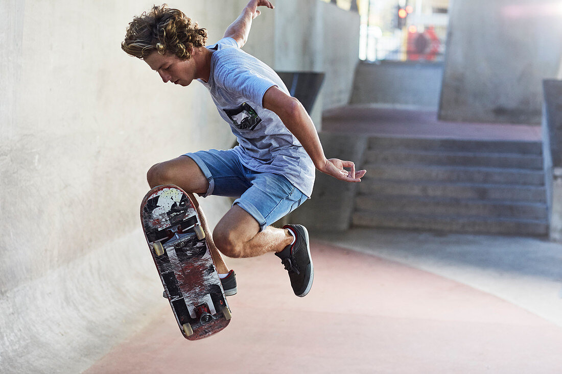 Boy flipping skateboard at skate park