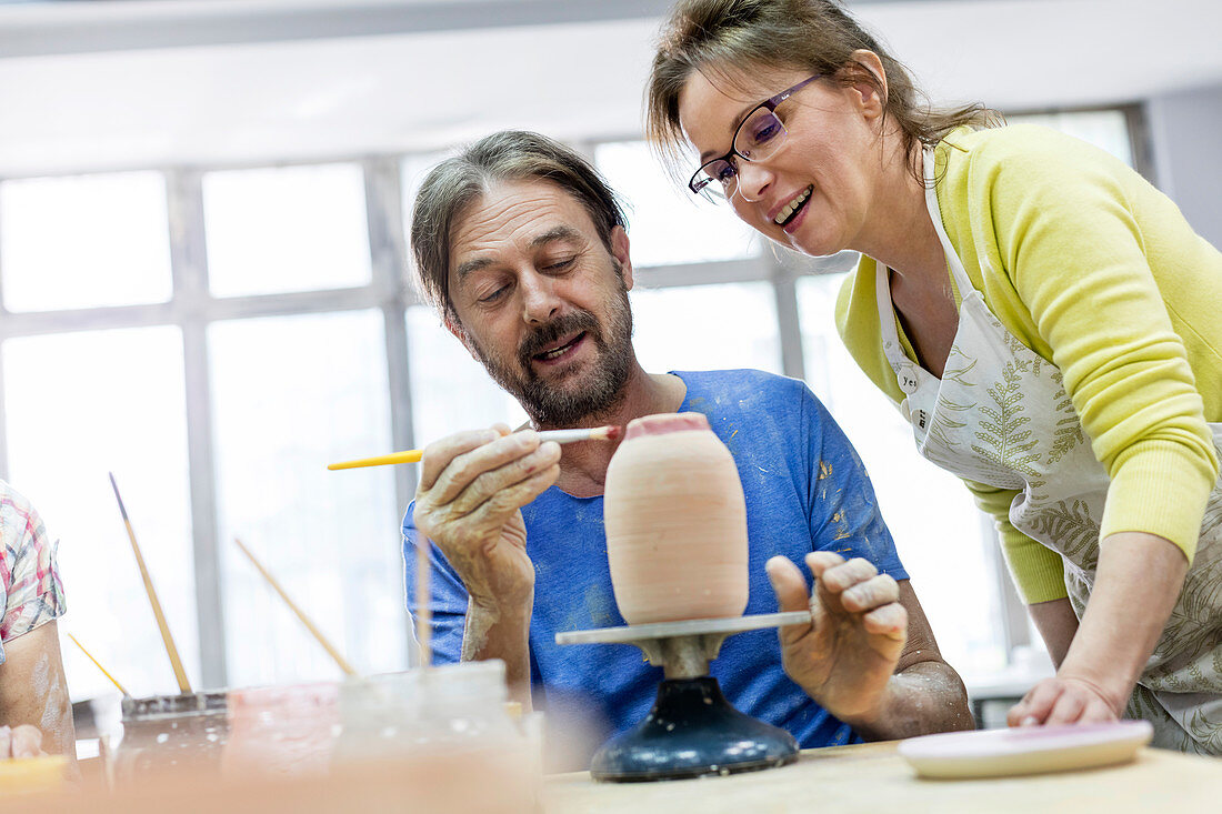 Mature couple painting pottery in studio