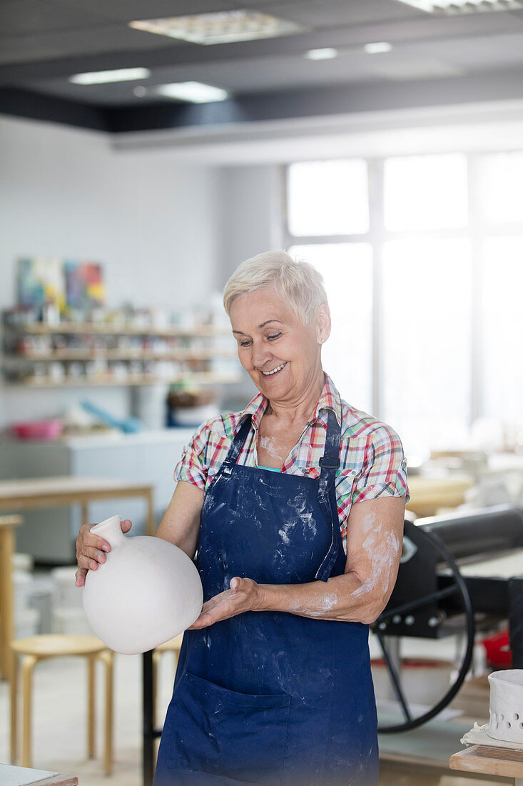 Smiling senior woman holding pottery vase
