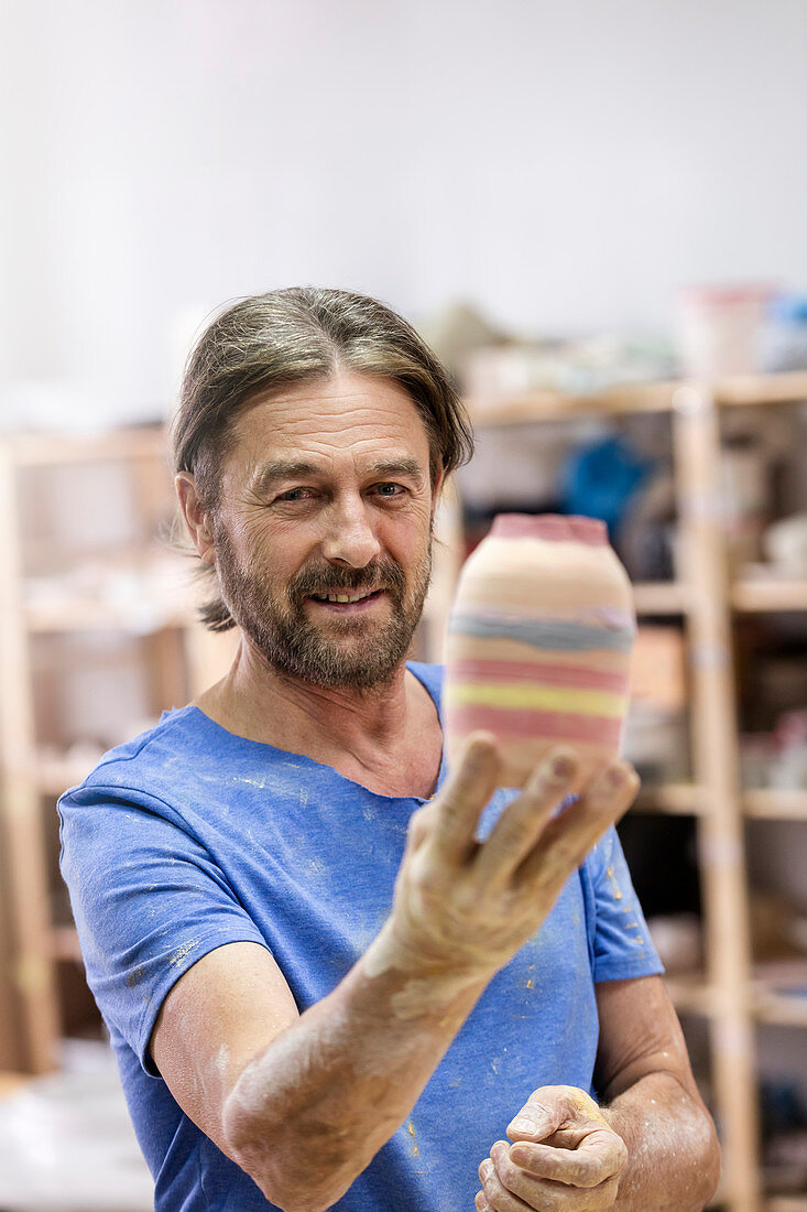 Mature man holding painted pottery vase
