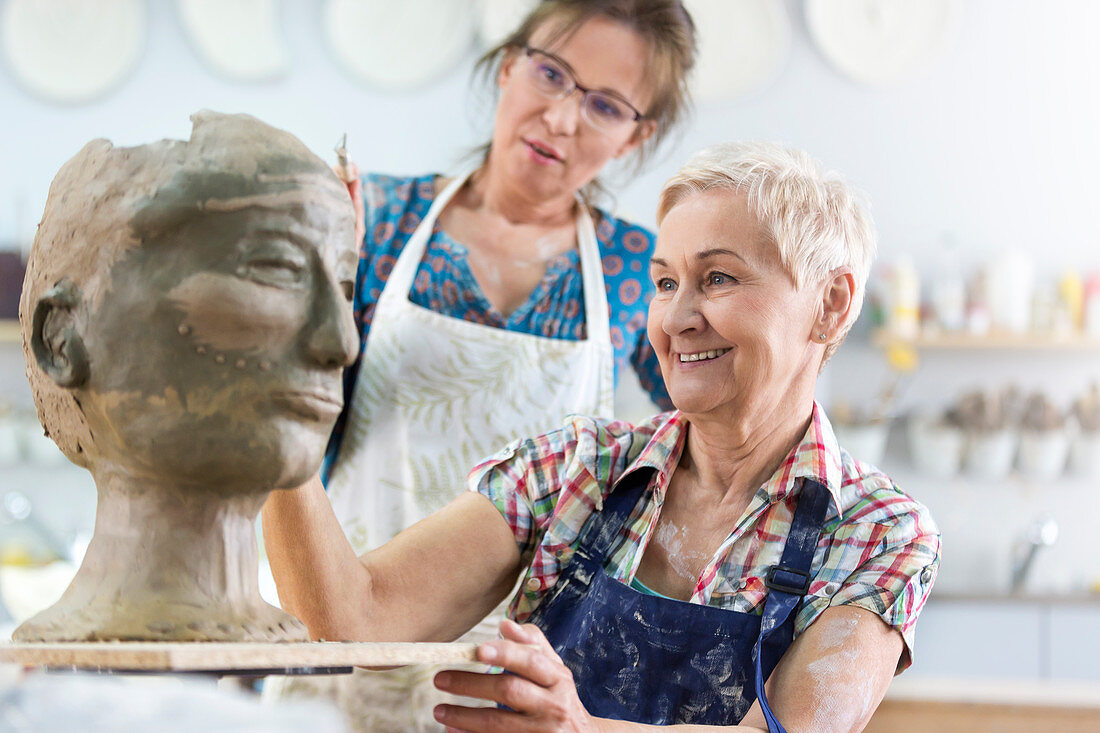 Senior woman sculpting clay face