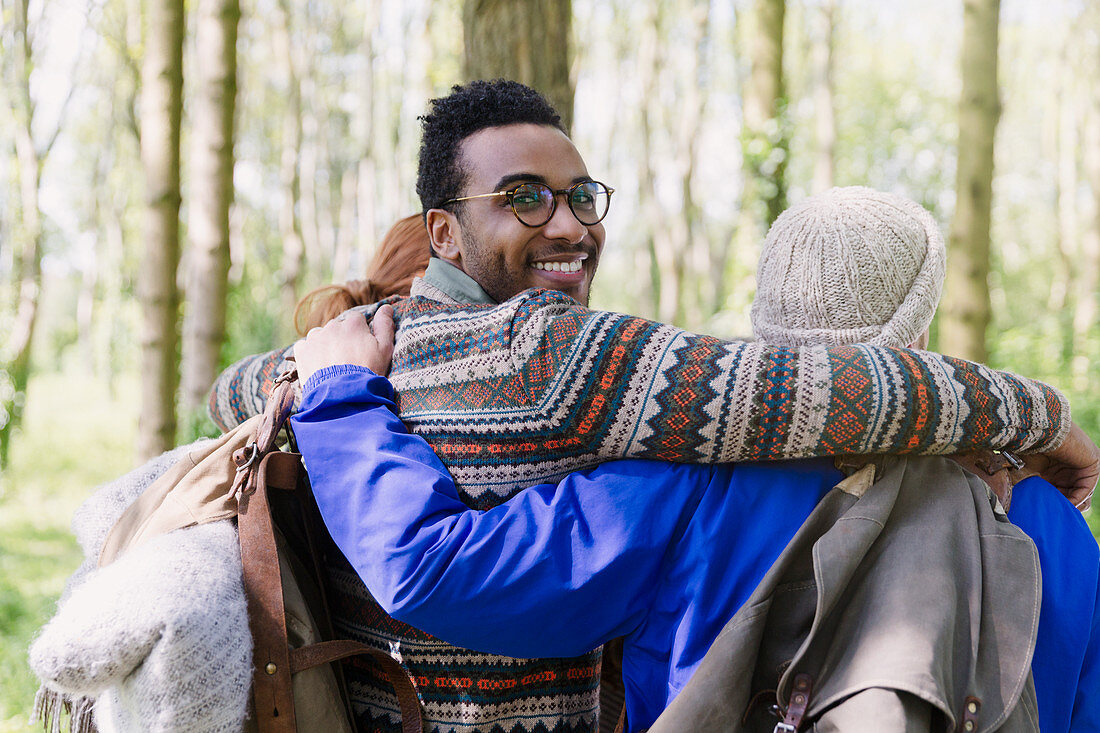 Smiling man hugging friends hiking