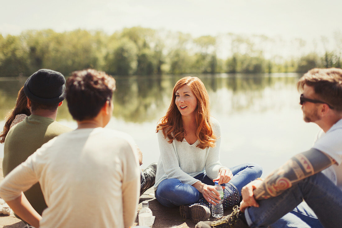 Friends talking at sunny lakeside