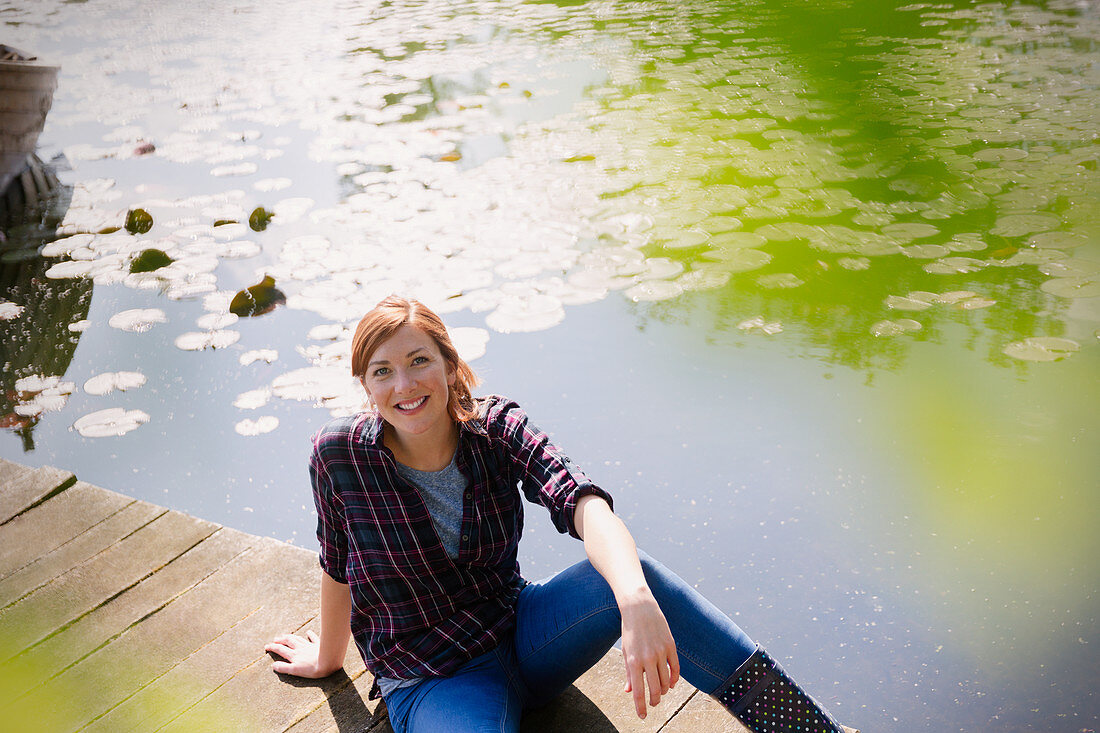 Woman sitting on sunny lakeside dock