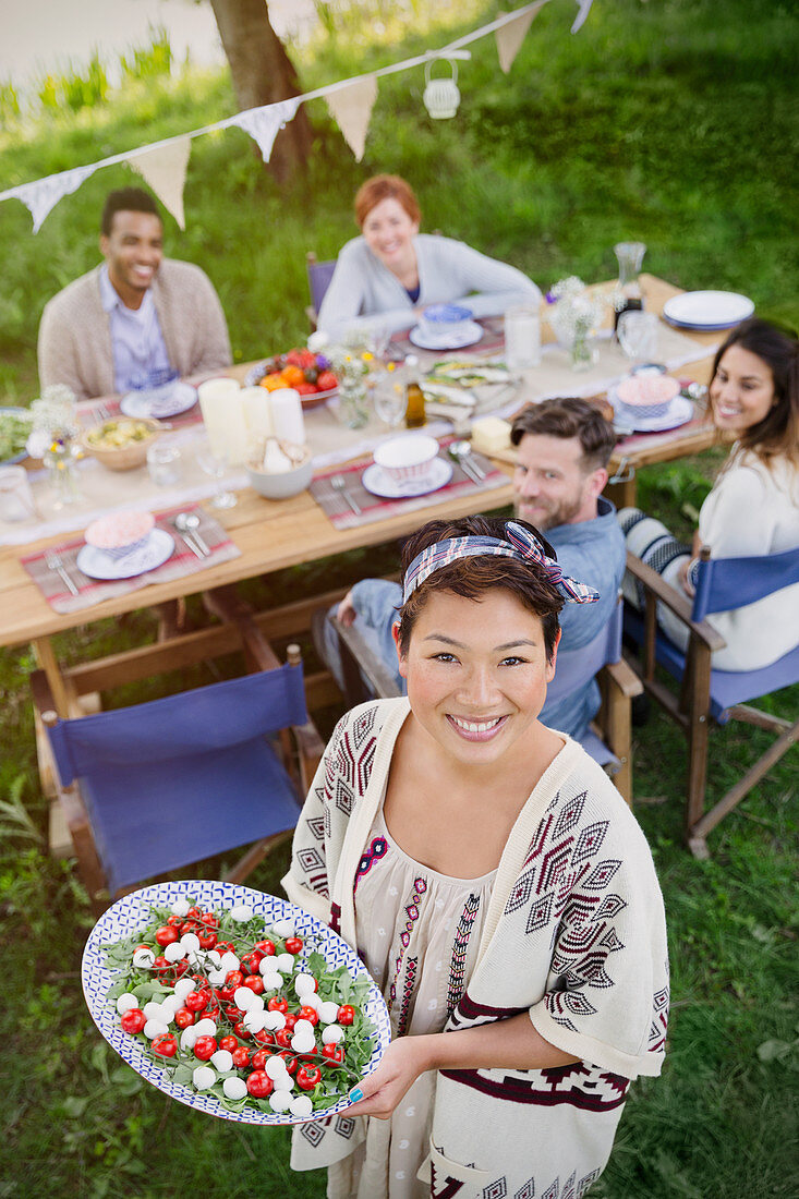 Woman serving Caprese salad to friends