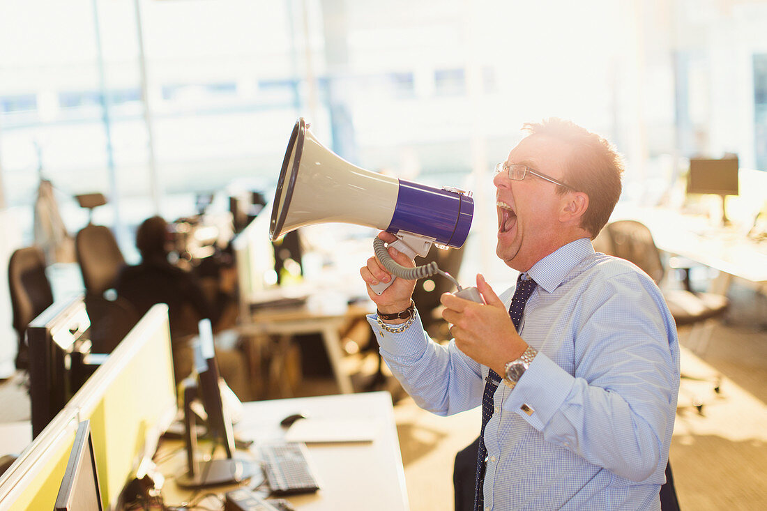 Businessman shouting into megaphone in office