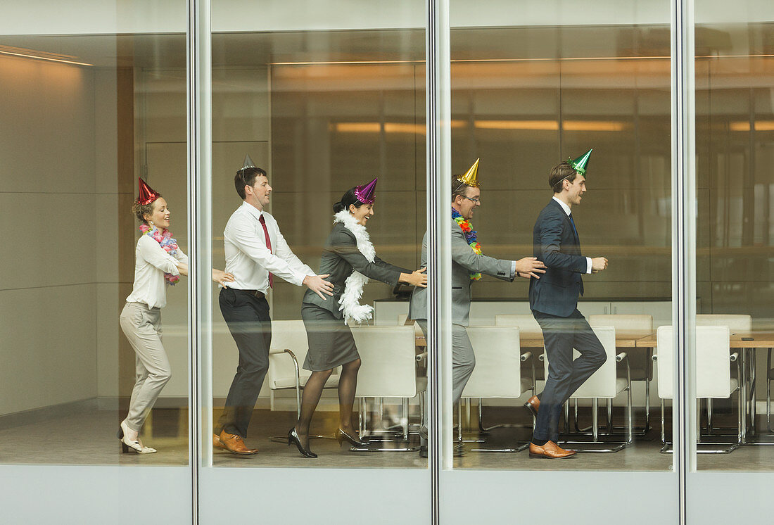 Business people wearing party hats and dancing