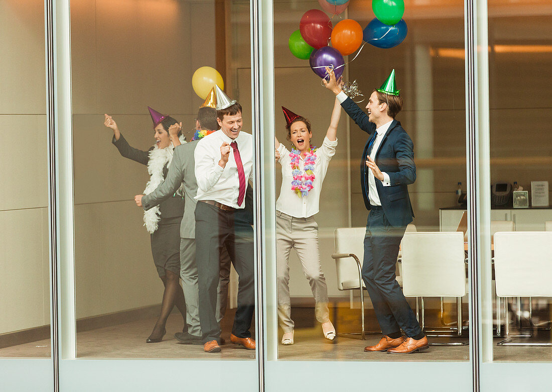 Business people wearing party hats and dancing