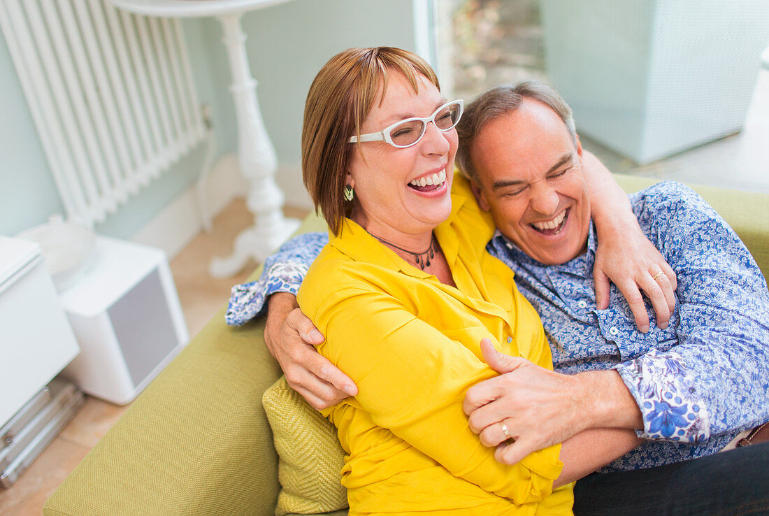 Mature couple laughing and hugging on sofa