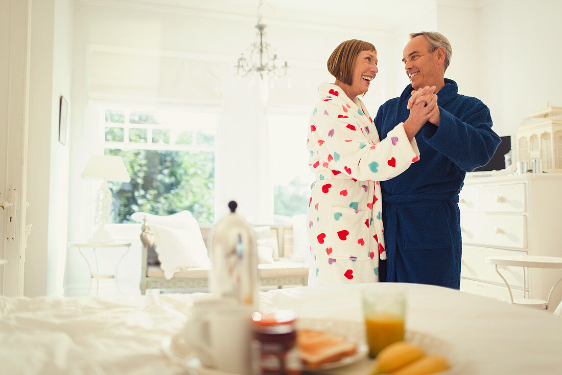 Mature couple dancing in bathrobes in bedroom