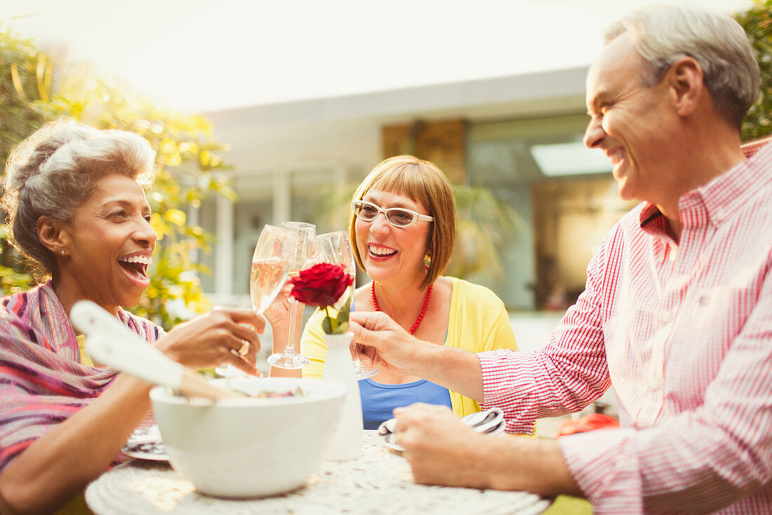 Mature friends toasting champagne flutes in garden