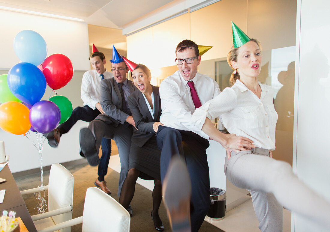 Business people with party hats dancing