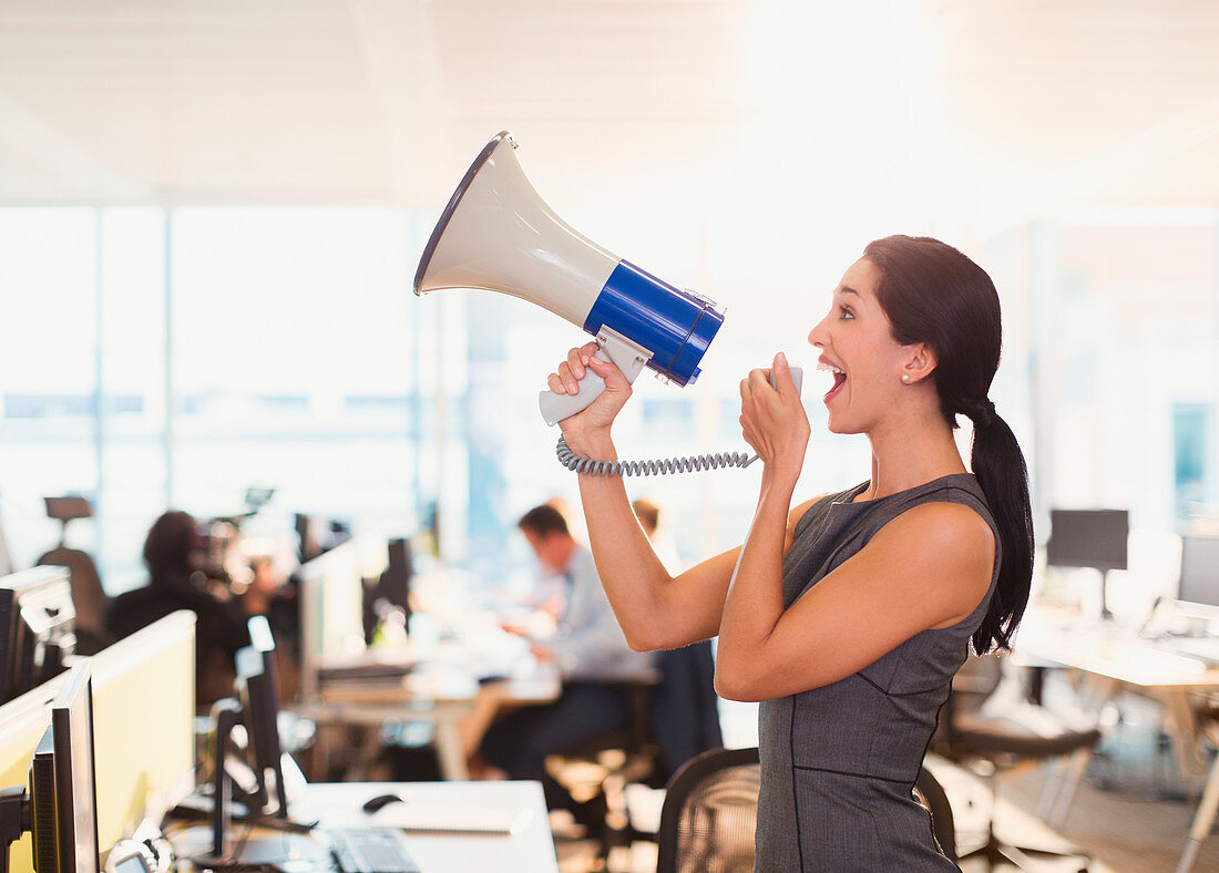 Exuberant businesswoman using megaphone in office
