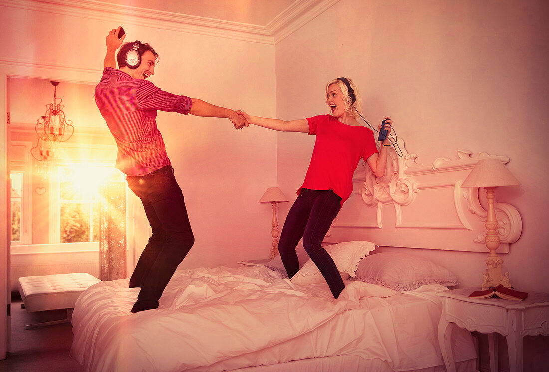 Couple dancing on bed listening to music