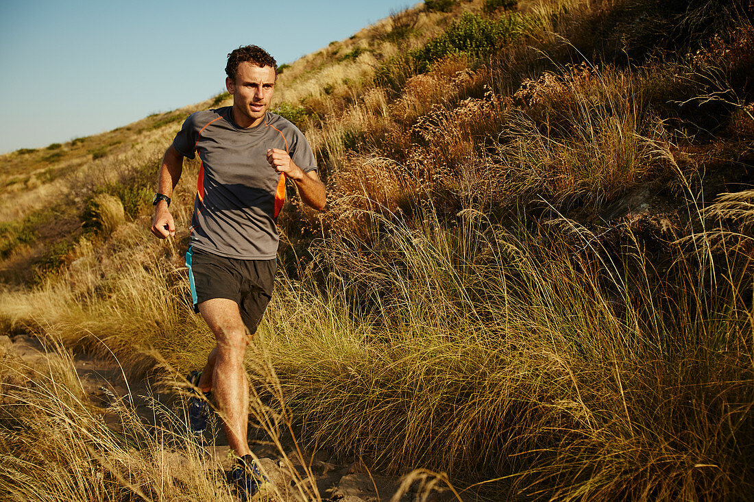 Man running on trail through tall grass