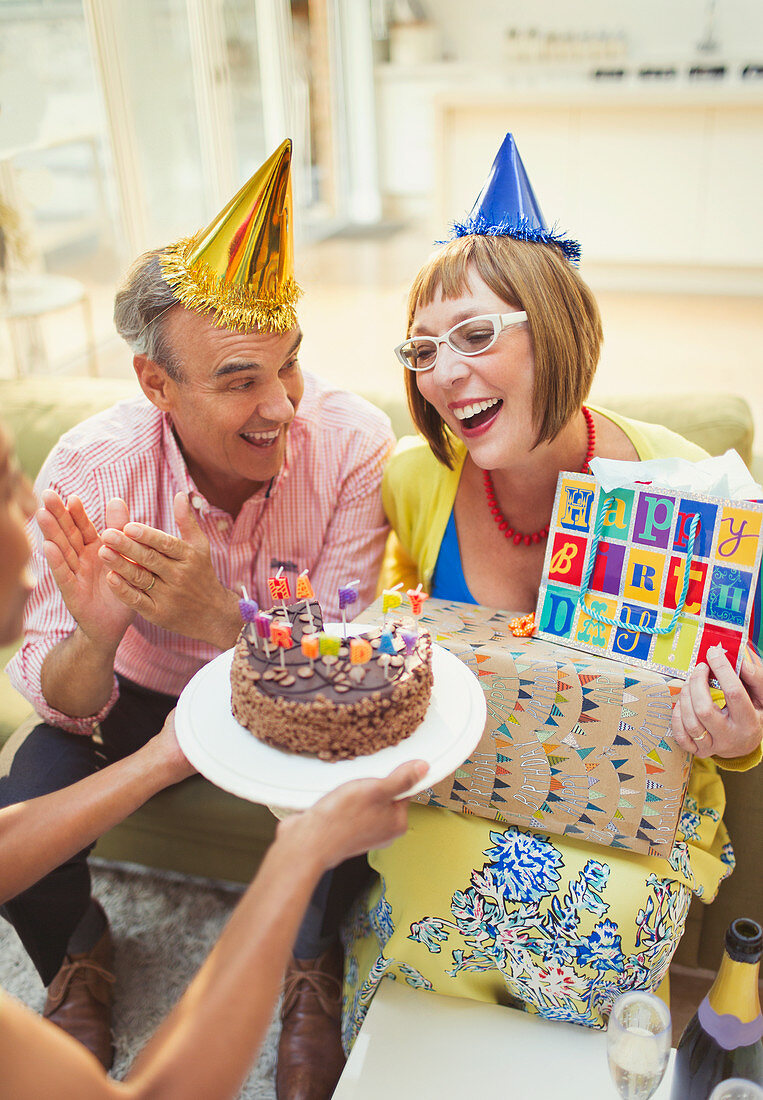 Mature women receiving birthday cake and gifts