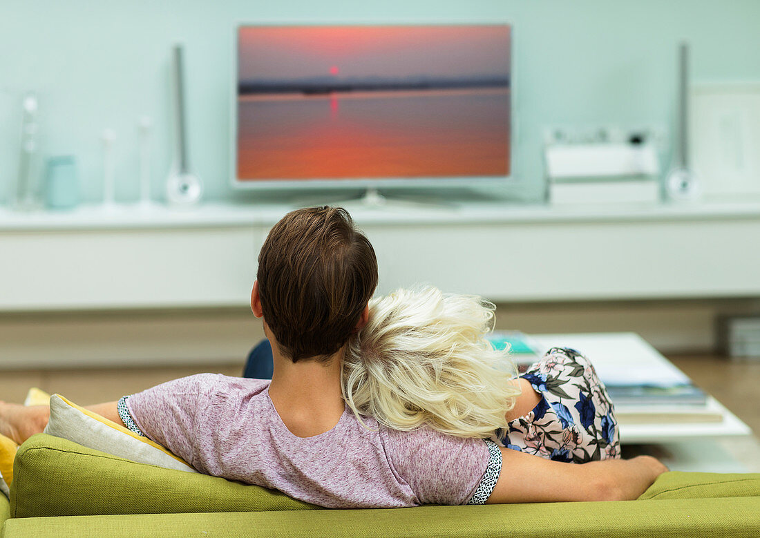 Relaxed couple watching TV on living room sofa