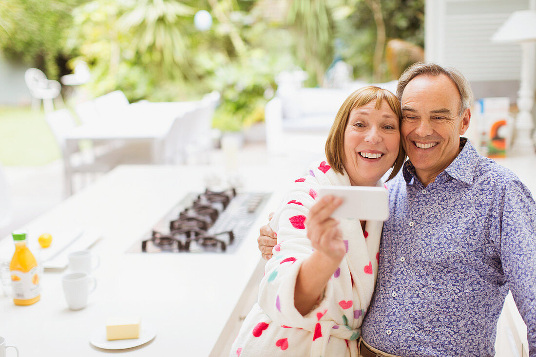 Smiling mature couple taking selfie in kitchen