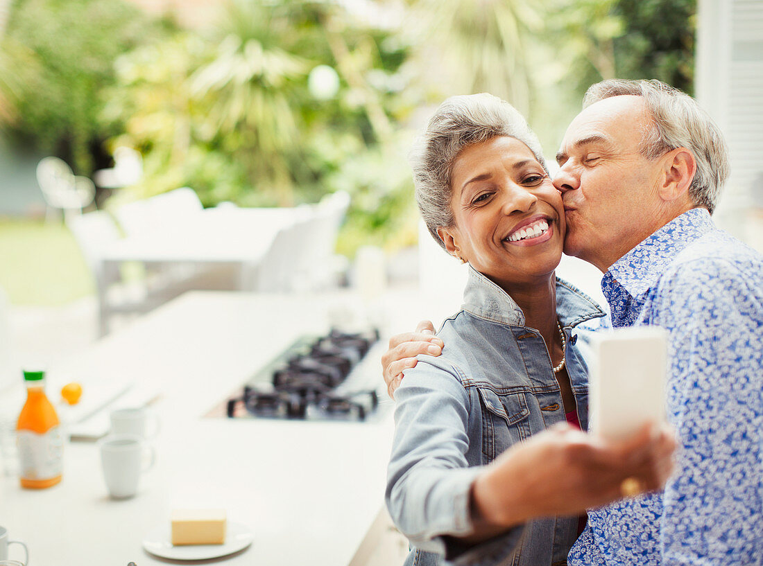 Affectionate mature couple kissing taking selfie