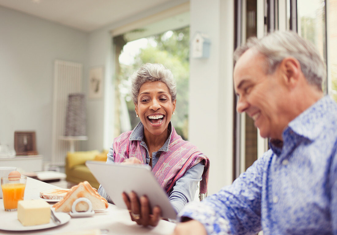 Mature couple laughing and using digital tablet