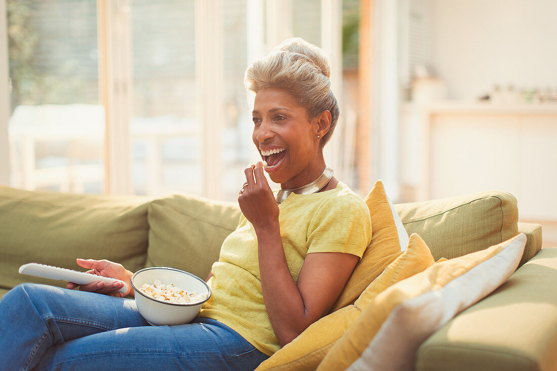 Mature woman eating popcorn and watching TV