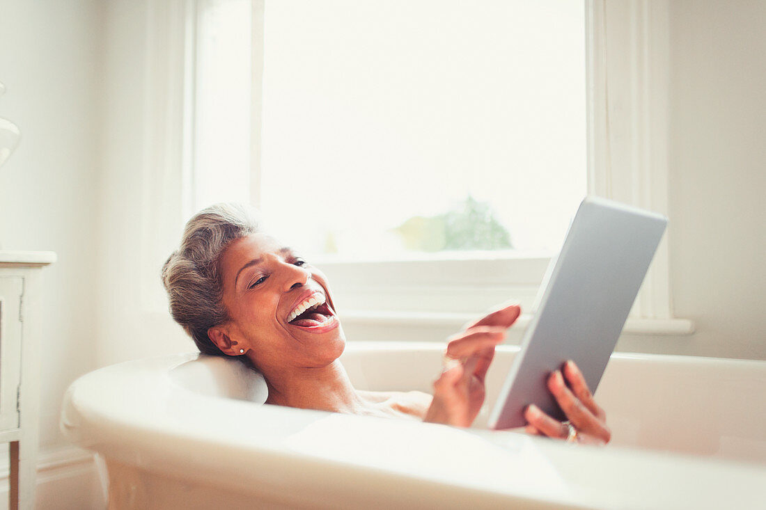 Mature woman using digital tablet in bathtub