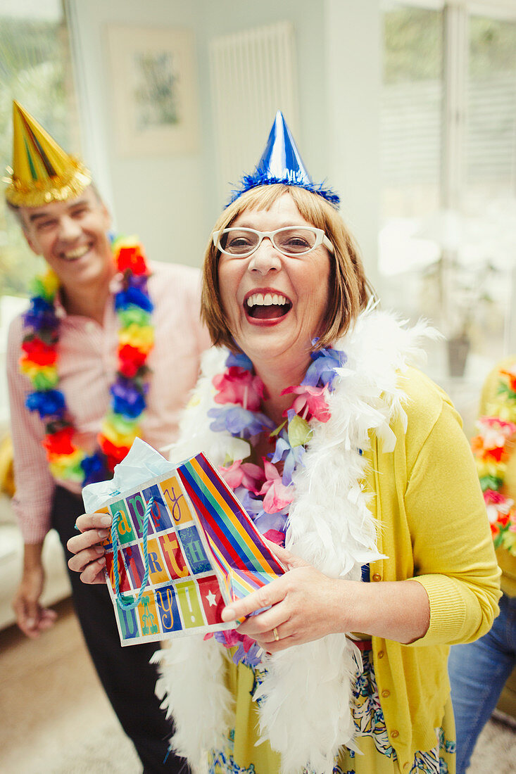 Mature woman in party hat holding birthday gift