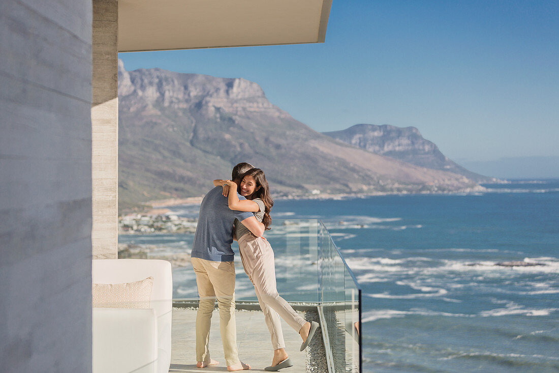 Couple hugging on sunny luxury balcony