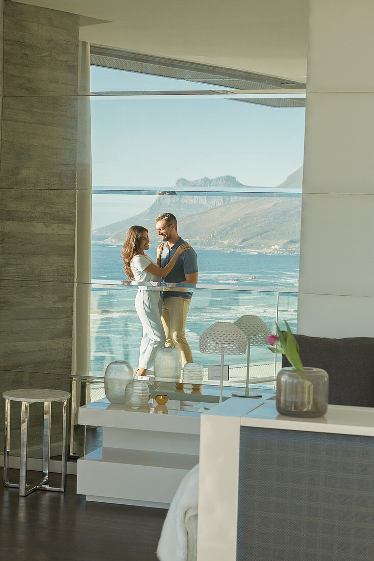 Reflection of couple hugging on luxury balcony