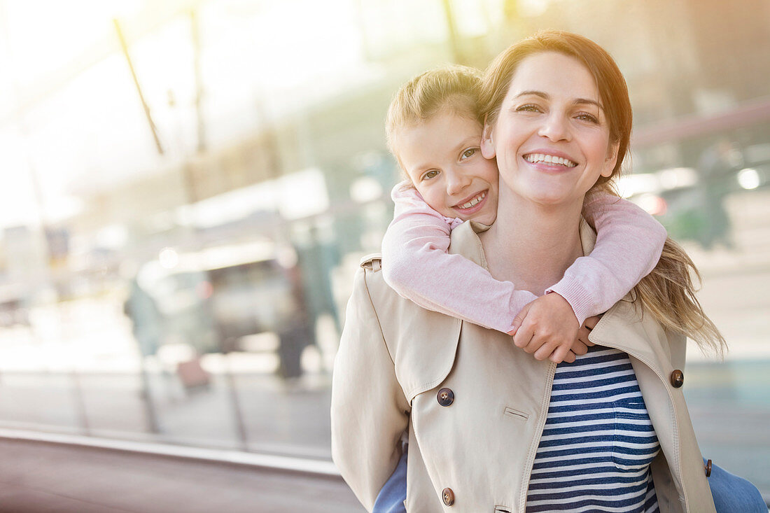 Portrait smiling mother piggybacking daughter