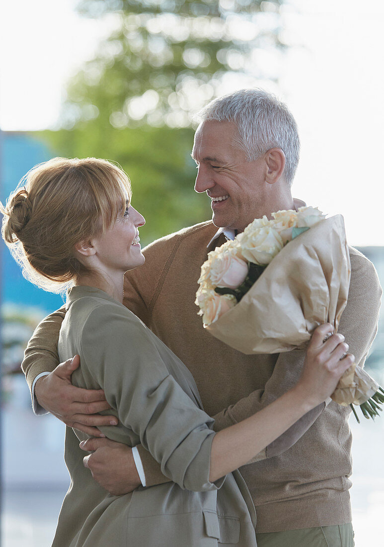 Smiling couple with flower bouquet hugging