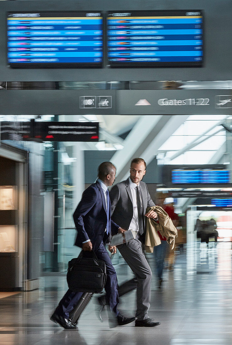 Businessmen running rushing in airport concourse
