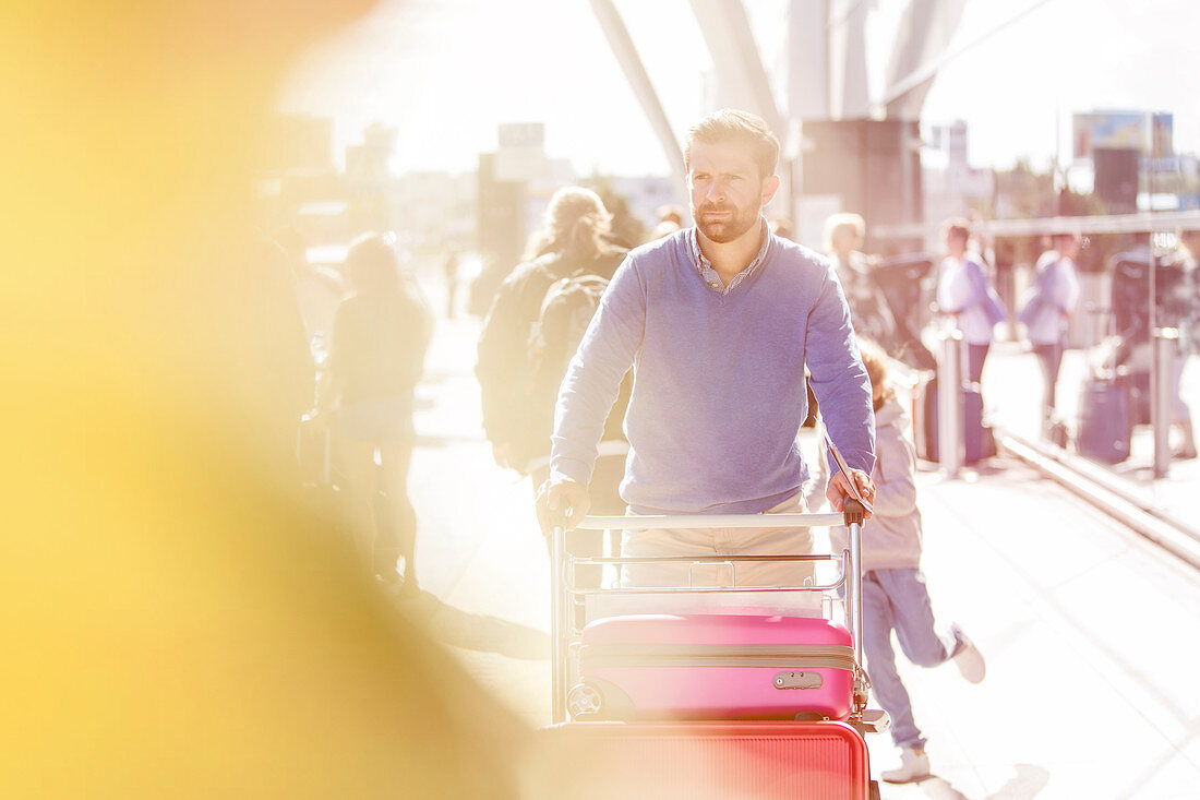 Man pushing luggage cart outside airport