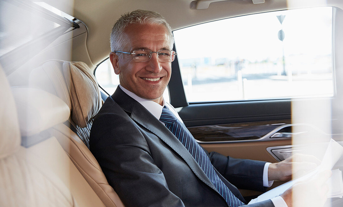Smiling businessman riding in back seat of car