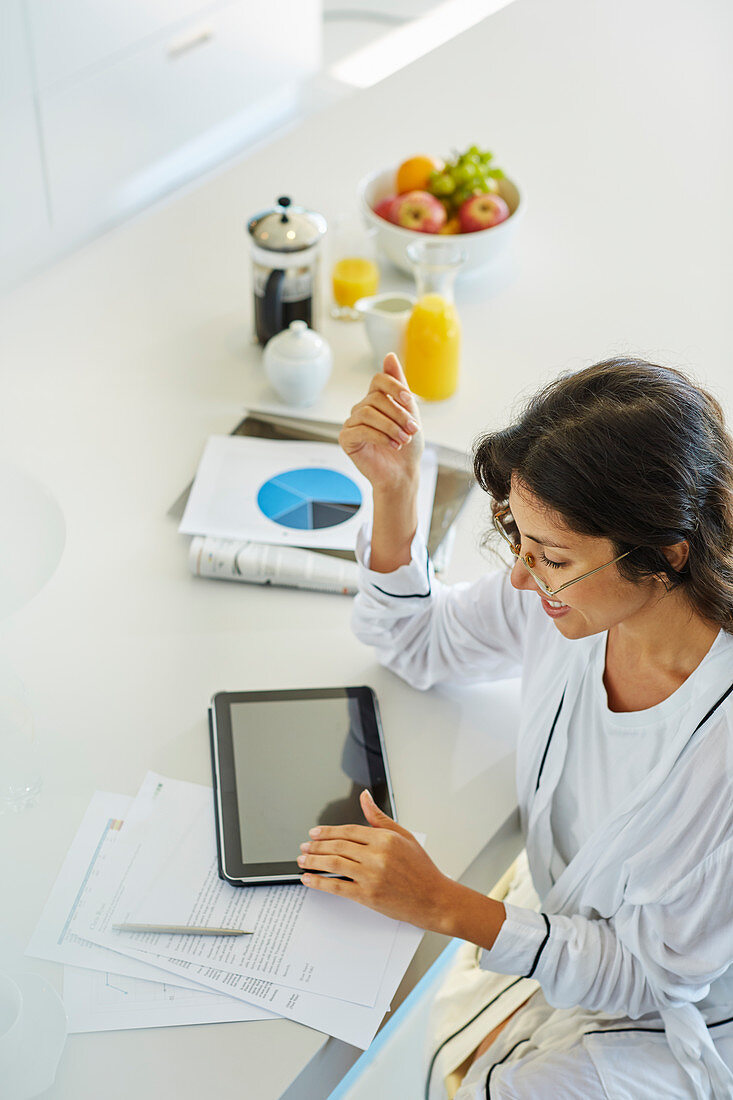 Woman working at digital tablet at kitchen counter