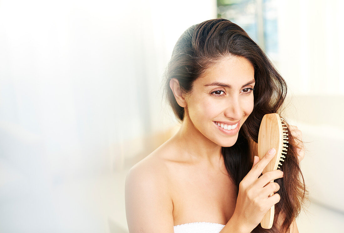 Smiling brunette woman brushing hair