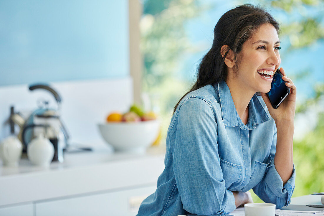Smiling woman talking on cell phone in kitchen