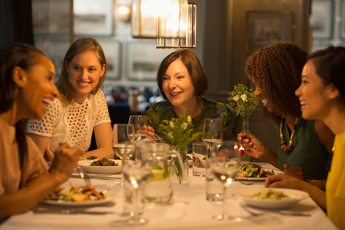 Smiling women friends dining at restaurant table