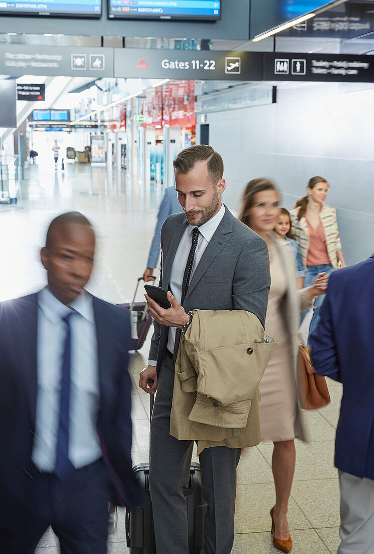 Businessman using cell phone in airport concourse