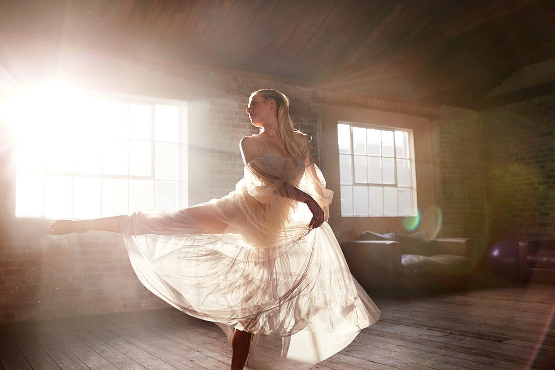 Graceful female dancer dancing in sunny studio