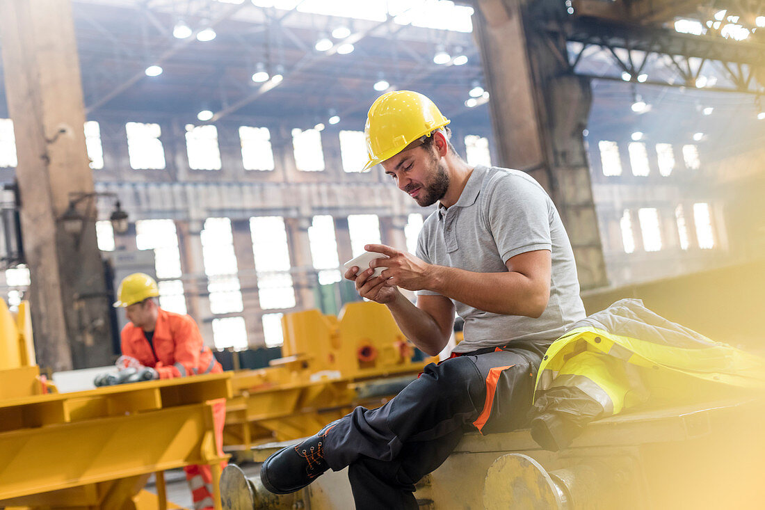 Steel worker texting taking a break in factory