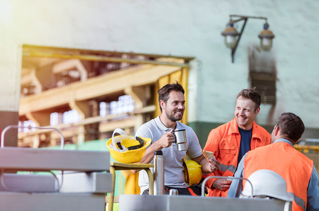 Smiling steel workers enjoying coffee break