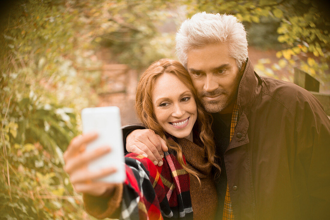 Couple hugging taking selfie in garden