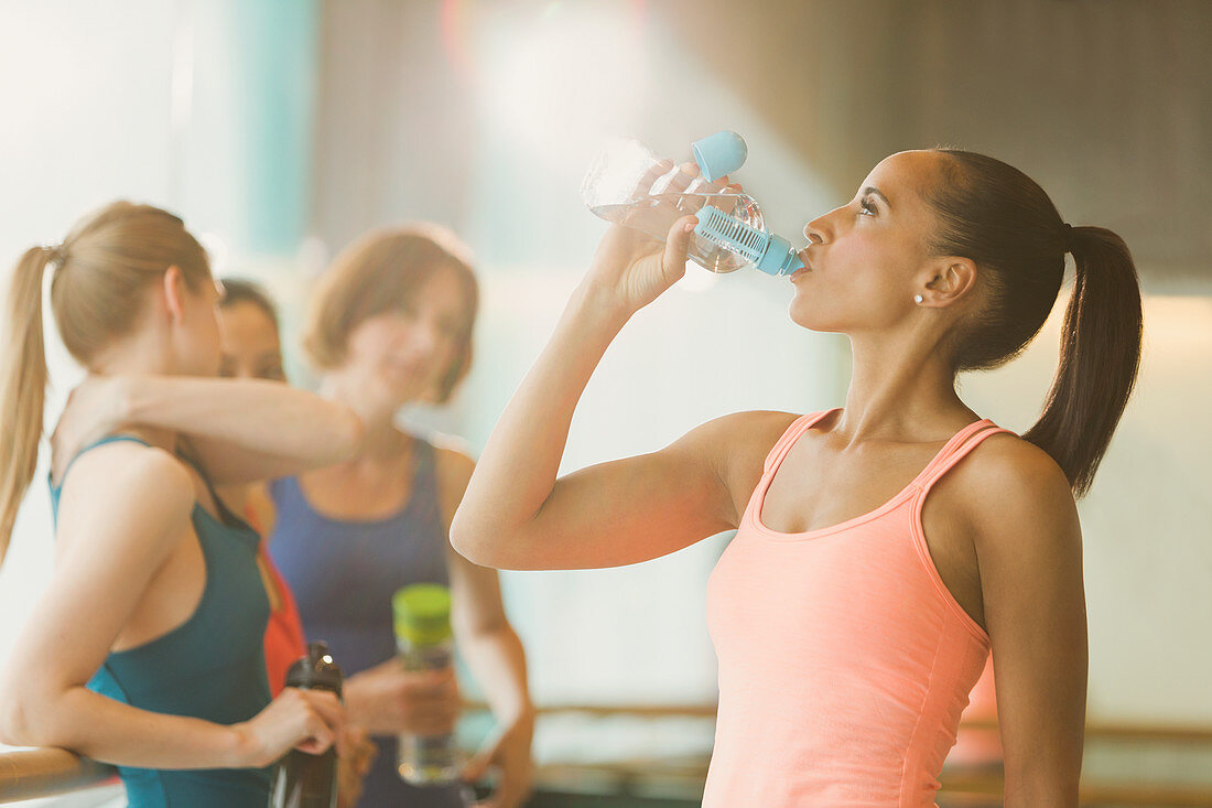 Woman drinking water in exercise class gym studio