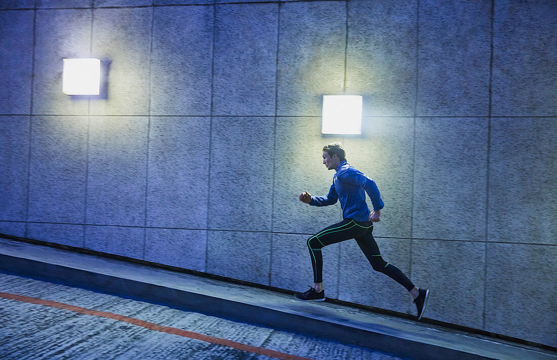 Male runner running ascending urban ramp