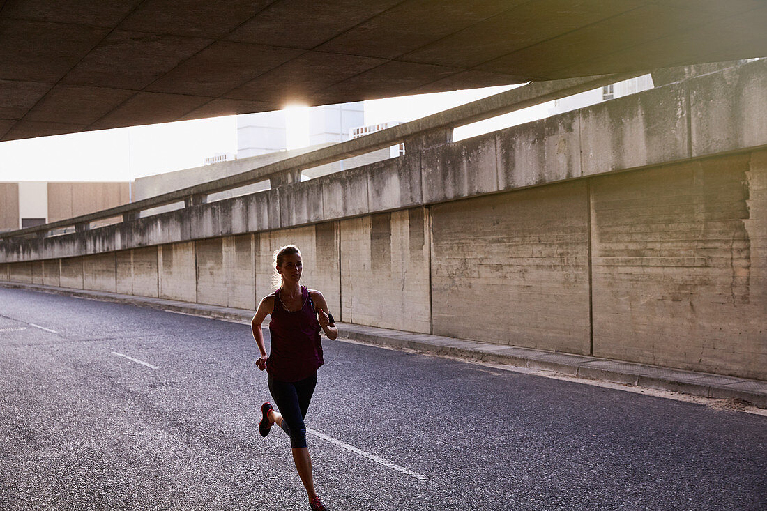 Female runner running into urban tunnel