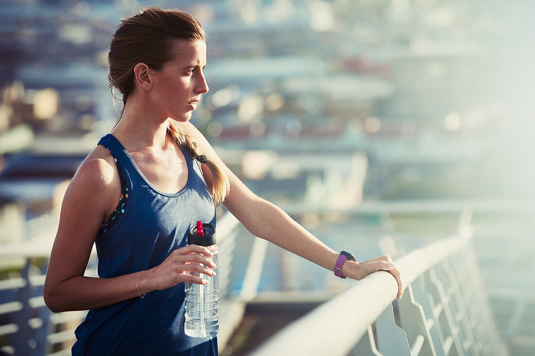 Female runner with water bottle resting